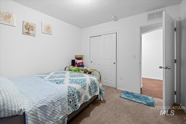 bedroom with a closet, a textured ceiling, and carpet flooring