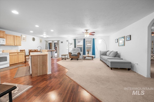 living room featuring ceiling fan, sink, a textured ceiling, and dark hardwood / wood-style flooring