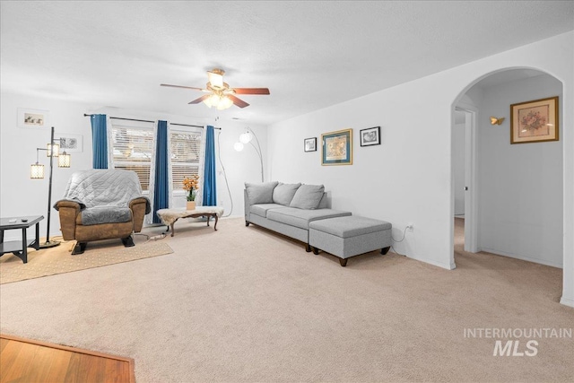 carpeted living room with a textured ceiling and ceiling fan