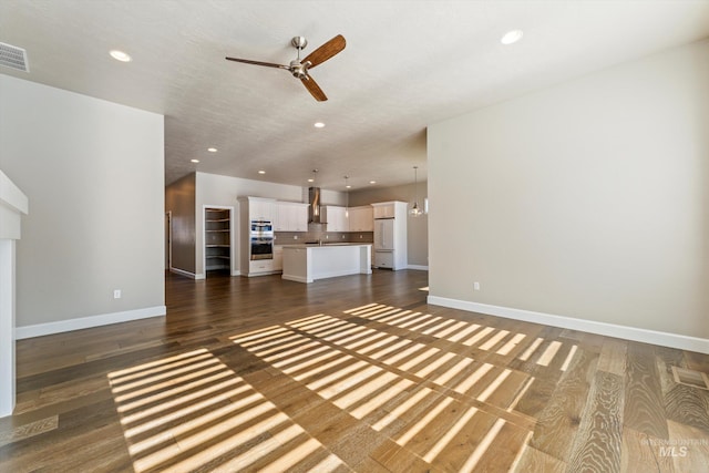 unfurnished living room with dark hardwood / wood-style flooring and ceiling fan