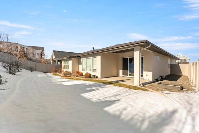 snow covered rear of property featuring a patio area and ceiling fan