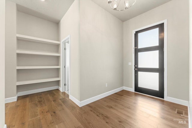 entryway with an inviting chandelier and wood-type flooring