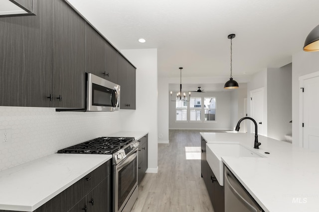 2827 N Rocky Bottom Way, Kuna, ID 83634 - kitchen featuring appliances with stainless steel finishes, light wood-style floors, decorative backsplash, a sink, and a chandelier