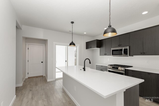 2827 N Rocky Bottom Way, Kuna, ID 83634 - kitchen featuring appliances with stainless steel finishes, a sink, light countertops, decorative backsplash, and light wood-style floors