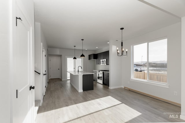 2827 N Rocky Bottom Way, Kuna, ID 83634 - kitchen featuring stainless steel appliances, baseboards, an island with sink, light wood finished floors, and light countertops