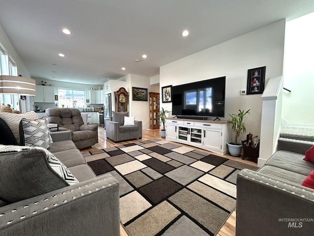 living room featuring stairs, recessed lighting, light wood-style floors, and baseboards