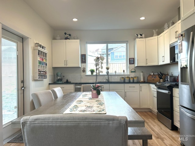 kitchen featuring light wood-style flooring, recessed lighting, appliances with stainless steel finishes, white cabinetry, and backsplash