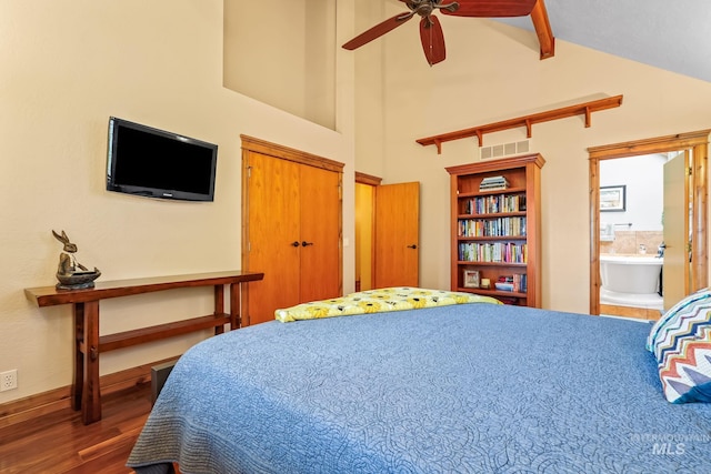 bedroom featuring high vaulted ceiling, wood finished floors, ensuite bathroom, beamed ceiling, and baseboards