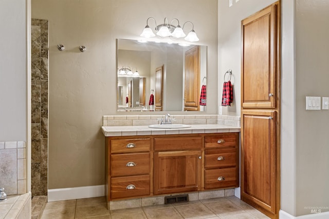 bathroom with vanity, a tile shower, and tile patterned floors