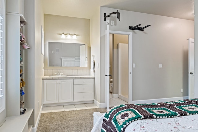 bedroom with light carpet, connected bathroom, and sink