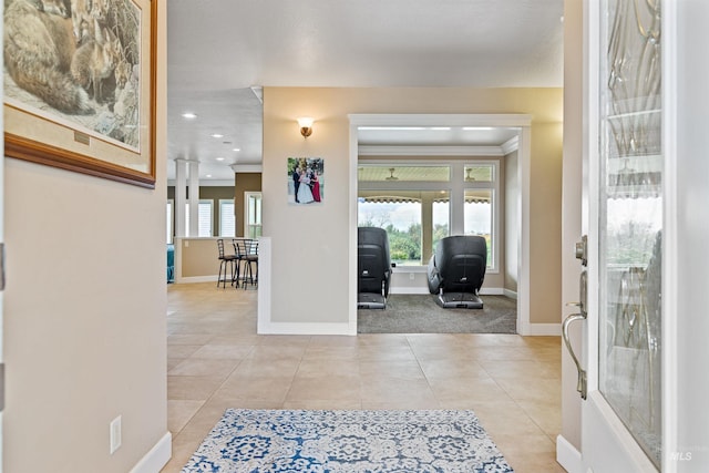 foyer with ornamental molding and light tile patterned floors