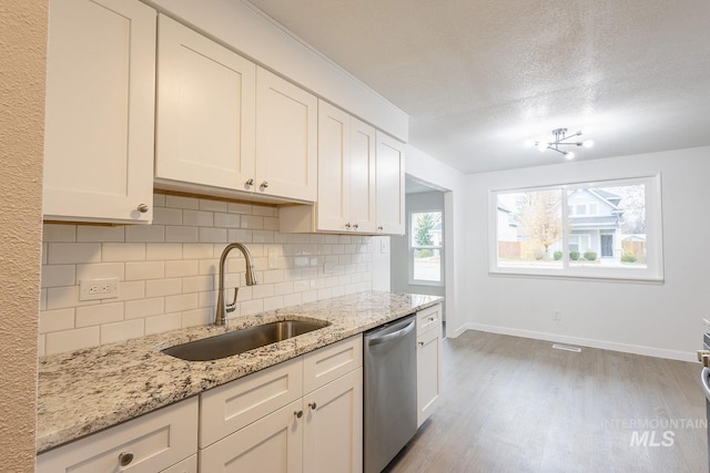 kitchen featuring sink, white cabinetry, tasteful backsplash, stainless steel dishwasher, and light stone countertops