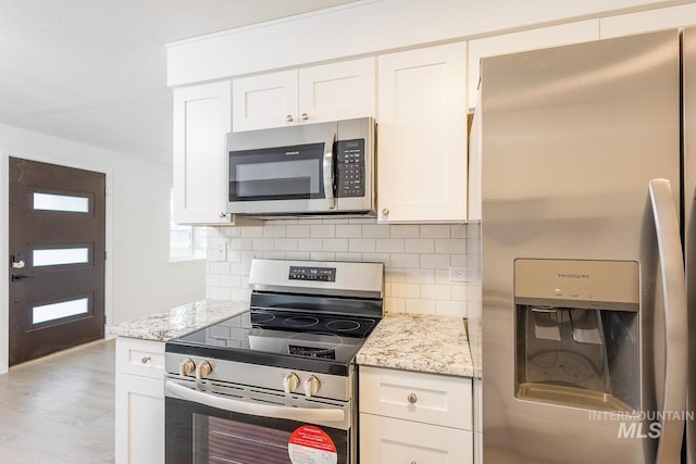 kitchen featuring white cabinetry, stainless steel appliances, tasteful backsplash, light stone countertops, and light hardwood / wood-style floors