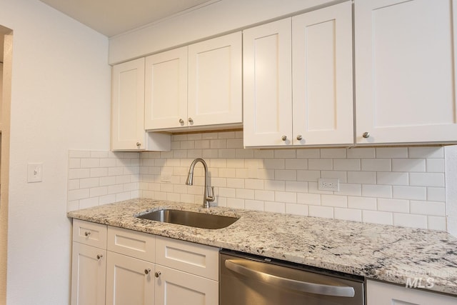 kitchen with tasteful backsplash, sink, stainless steel dishwasher, and white cabinets