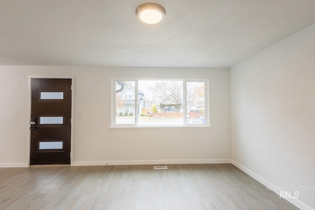 entryway with a textured ceiling and light wood-type flooring