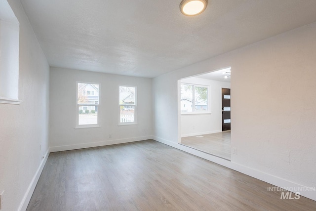 unfurnished room with a textured ceiling and light wood-type flooring