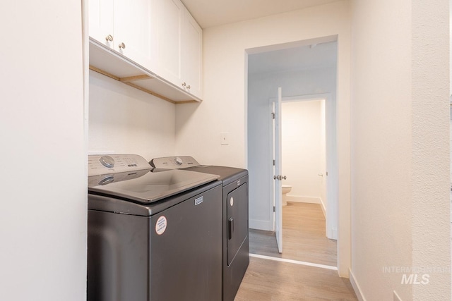 laundry room with cabinets, washing machine and dryer, and light wood-type flooring