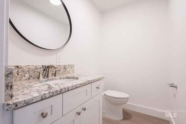 bathroom with hardwood / wood-style flooring, vanity, and toilet