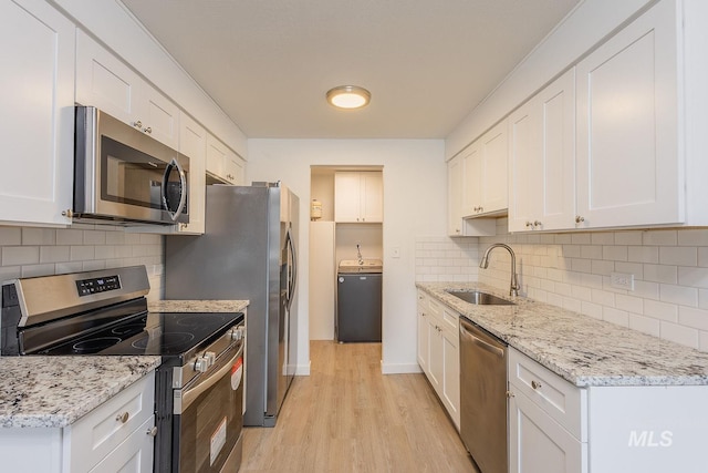 kitchen featuring stainless steel appliances, washer / clothes dryer, and white cabinets