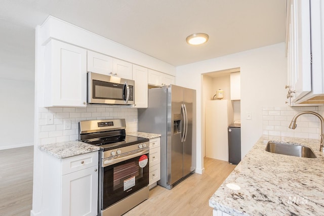 kitchen featuring white cabinetry, appliances with stainless steel finishes, light stone countertops, and sink