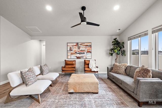 living area featuring baseboards, visible vents, ceiling fan, vaulted ceiling, and a textured ceiling