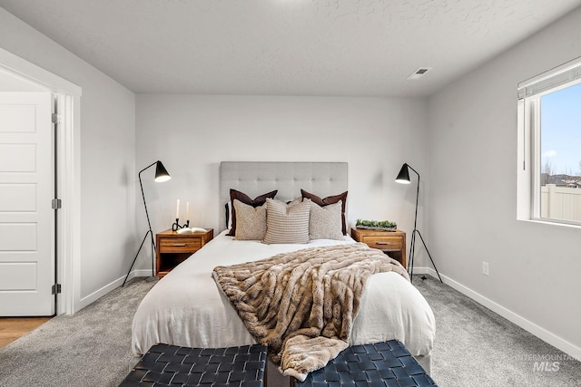 carpeted bedroom with visible vents, baseboards, and a textured ceiling