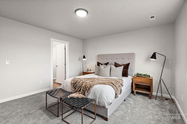 bedroom featuring carpet flooring, visible vents, a textured ceiling, and baseboards