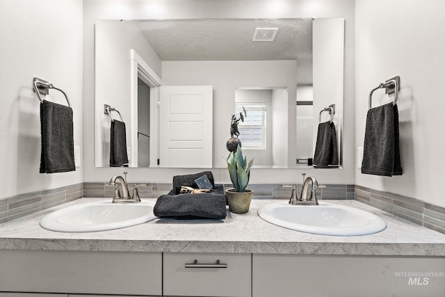 bathroom with a sink, visible vents, and double vanity