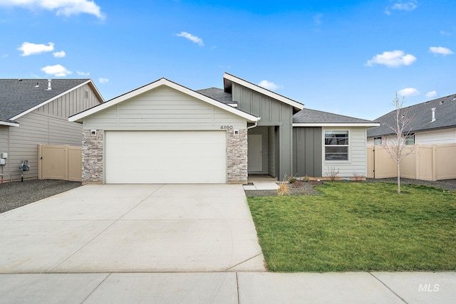 view of front of property featuring a front lawn, driveway, fence, board and batten siding, and an attached garage