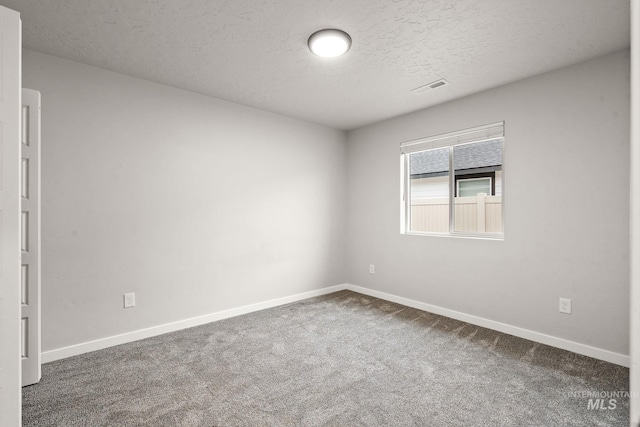 carpeted empty room featuring visible vents, baseboards, and a textured ceiling