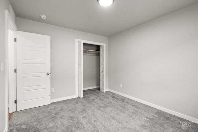 unfurnished bedroom with baseboards, carpet floors, and a closet