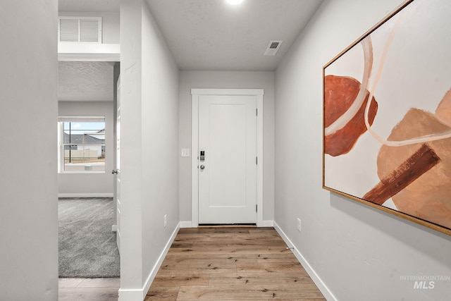 entryway with baseboards, wood finished floors, visible vents, and a textured ceiling