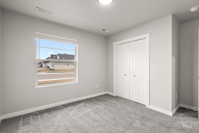 unfurnished bedroom with carpet flooring, baseboards, visible vents, and a textured ceiling