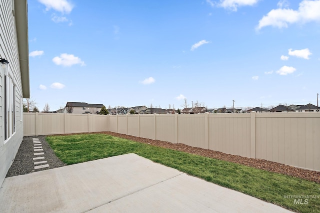 view of yard with a residential view, a fenced backyard, and a patio area