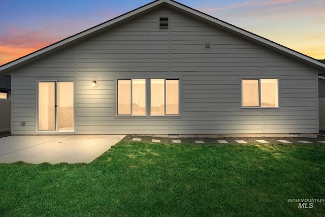 rear view of house with a patio area, a lawn, and crawl space