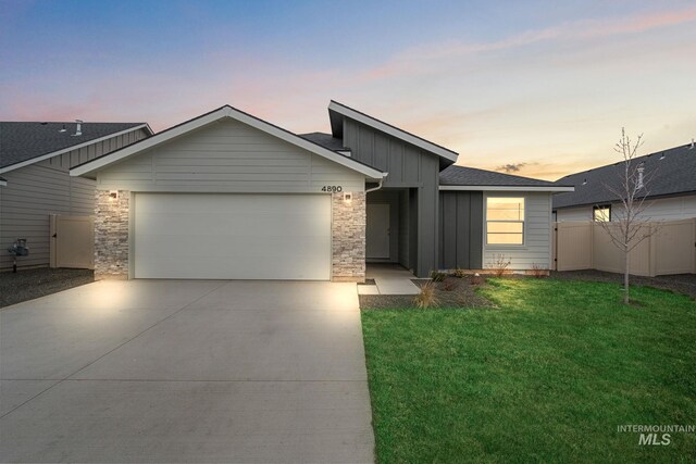 view of front of house with a lawn, fence, board and batten siding, concrete driveway, and an attached garage