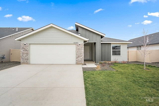 view of front of property with fence, concrete driveway, a front lawn, a garage, and board and batten siding