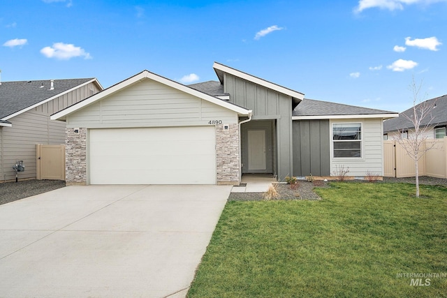 view of front of house with an attached garage, concrete driveway, a front lawn, stone siding, and board and batten siding