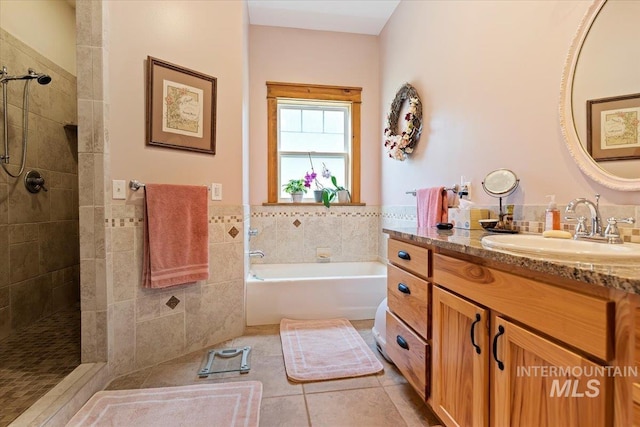 bathroom with tile walls, tile patterned floors, independent shower and bath, and vanity