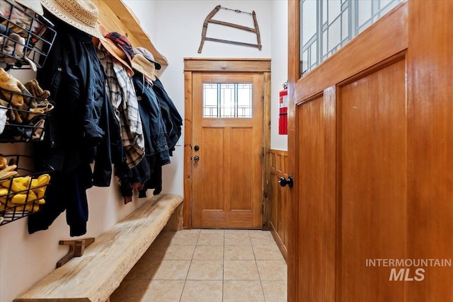 mudroom featuring light tile patterned flooring and wood walls