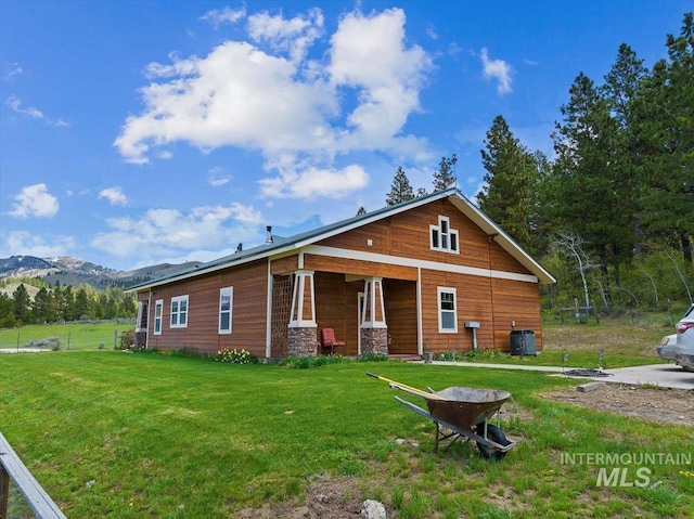 rear view of house featuring cooling unit, a mountain view, and a lawn