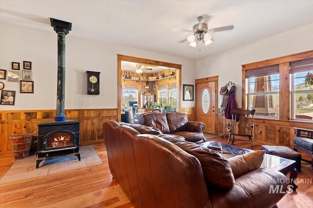 living room featuring ceiling fan, light hardwood / wood-style flooring, and a wood stove