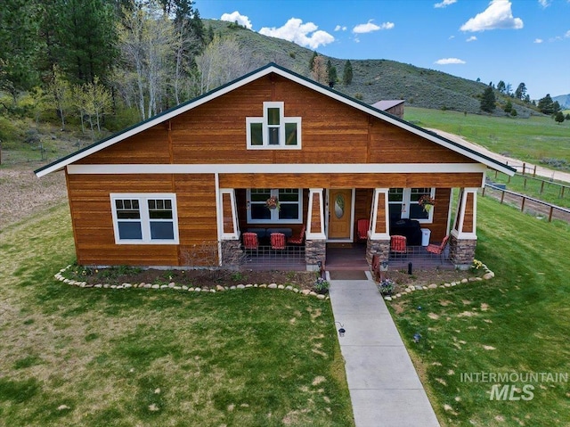 view of front facade featuring a porch, a front lawn, and a mountain view