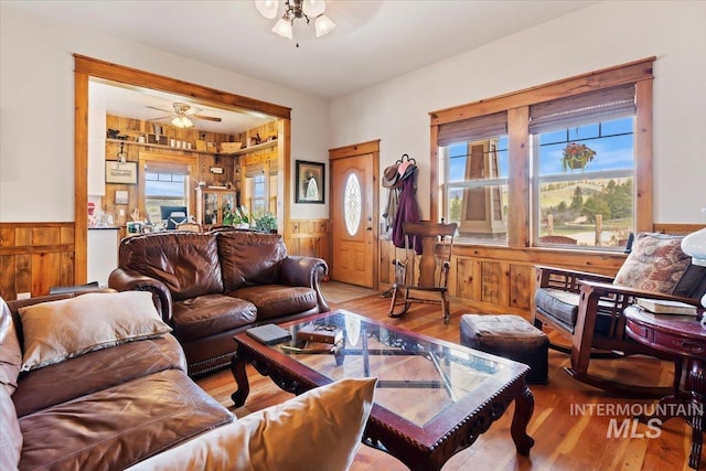 living room with wooden walls, hardwood / wood-style floors, and ceiling fan