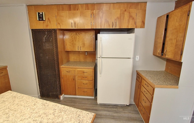 kitchen featuring brown cabinets, freestanding refrigerator, light countertops, and wood finished floors