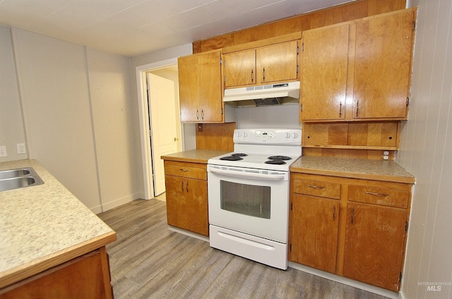 kitchen with electric stove, brown cabinets, light countertops, light wood-style floors, and under cabinet range hood