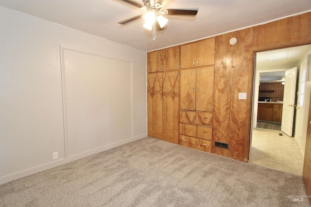 unfurnished bedroom with attic access, visible vents, a ceiling fan, carpet floors, and a closet