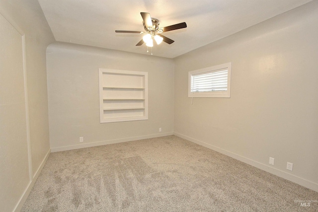 empty room featuring carpet floors, baseboards, built in features, and ceiling fan