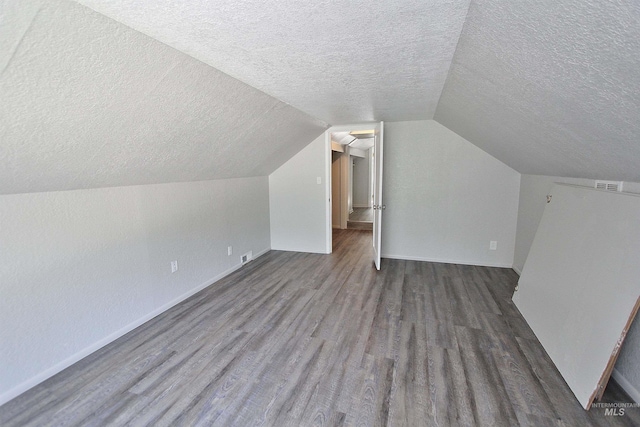 bonus room with visible vents, vaulted ceiling, a textured ceiling, wood finished floors, and baseboards