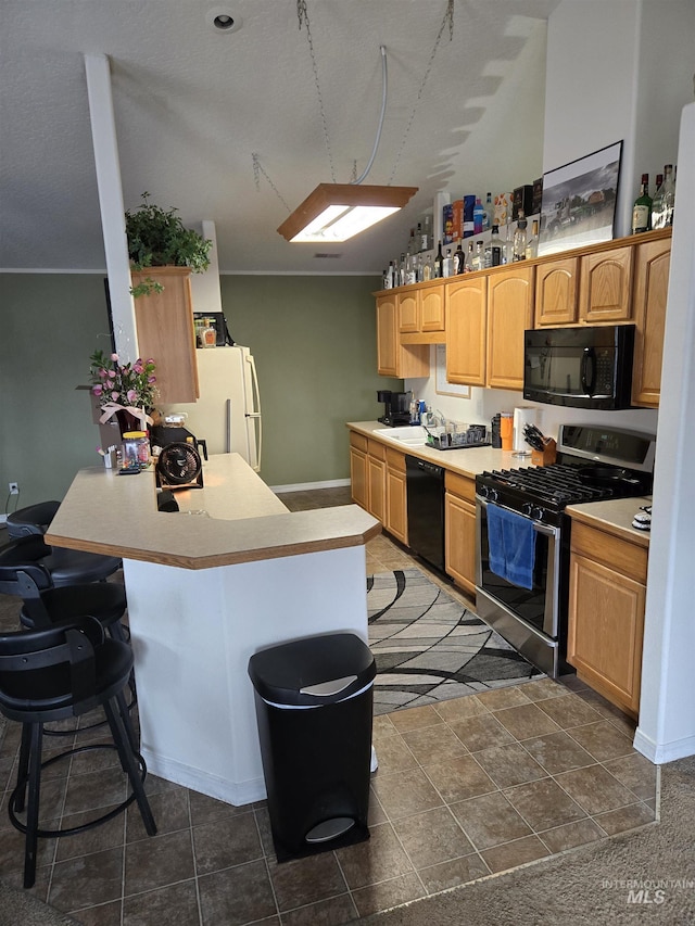 kitchen with a breakfast bar, light countertops, built in study area, a peninsula, and black appliances